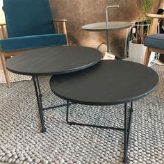 two black tables sitting on top of a rug next to a blue chair and table