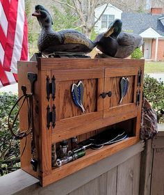 two ducks sitting on top of a wooden cabinet with an american flag in the background