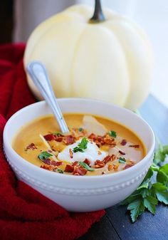 a white bowl filled with soup next to a pumpkin