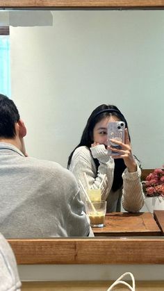 a woman taking a selfie in front of a mirror while sitting at a table