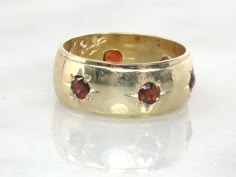 This Vintage 14k Gold Garnet Wedding Band is a showstopper! It features six garnets set in starburst shapes in a wide band. The genuine garnets are round and measure approximately 3 mm. The decoration goes all the way around. A very pretty and feminine design in yellow gold! The band measures approximately 8 mm wide with a rise of approximately 1.75 mm and is unmarked and tests for 14k gold. It has hand engraving inside that reads, J.E.P. B.M.S. 1-18-69. This ring is in good vintage condition an Vintage Band Ring, Gold Ring Vintage, Wedding Ring Art Deco, Weddinf Ring, 70s Wedding Ring, Gemstone Wedding Band, Round Garnet Jewelry Stamped 14k, Wedding Ring Vintage, Vintage Gold Ring