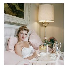 a woman laying in bed next to a lamp