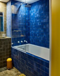 a blue tiled bathroom with a tub and shower