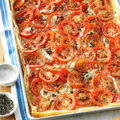 an uncooked pizza with tomatoes and herbs on top, ready to go into the oven