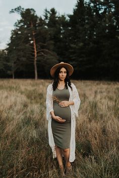 a pregnant woman wearing a hat in a field