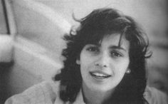 a black and white photo of a woman with long dark hair smiling at the camera