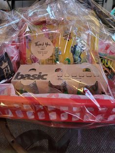 a basket filled with lots of different types of items in plastic wrap on top of a table