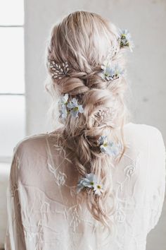 a woman with long hair and flowers in her hair is wearing a white blouse, while she