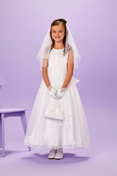 Lucinda is a truly luxurious ankle length Holy Communion dress. The sleeveless bodice has a ruched organza waistband and guipure appliques cascading down onto the skirt.  The hem of the  full net skirt is edged in matching scalloped lace detail for maximum impact. The dress has a large pre tied organza bow, is fastened with pearl buttons and is fully lined for maximum comfort. Available in White The dress is shown with the Rebecca gloves and Vivienne hair comb. Why not complete the look with our Fitted Organza Dress For Confirmation, Organza Lace Trim Dress For Confirmation, Fitted Sleeveless Gown For First Communion, Fitted Organza Gown For Confirmation, Sleeveless Tulle Gown For Confirmation, Organza Confirmation Dress With Lace Trim, Elegant Sleeveless Gown For Confirmation, White Delicate Lace First Communion Dress, White Sleeveless First Communion Dress With Lace Bodice