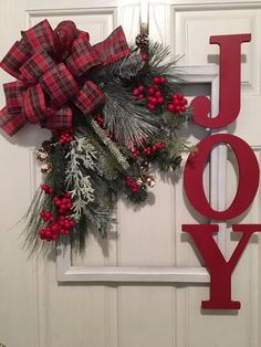 a christmas wreath with the word joy hanging from it's side on a door