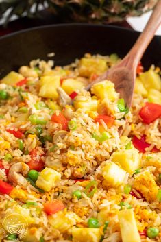 a pan filled with rice and vegetables next to a pineapple