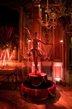 a statue stands in front of a chandelier with red lights on the walls