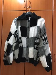 a black and white sweater hanging on a wooden door