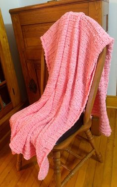 a pink blanket sitting on top of a wooden chair