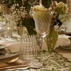 there is a vase with flowers in it on the dining room table set for dinner