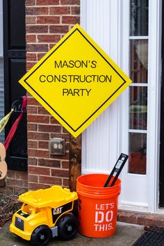 a yellow construction sign sitting on the side of a building next to a orange bucket