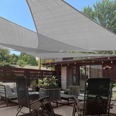 an outdoor patio area with chairs and tables under the awning, surrounded by trees