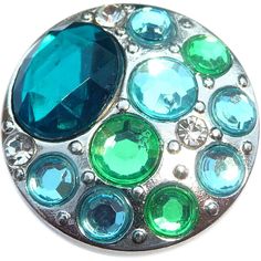 a green and blue brooch sitting on top of a white surface with lots of bubbles