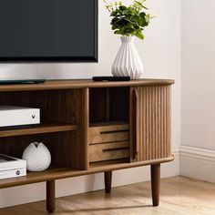 an entertainment center with a television on top of it and a plant in the corner