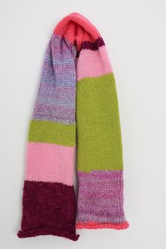 a pink, green and purple striped scarf on a white surface with the end rolled up