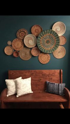 a wooden bench sitting in front of a wall with baskets hanging on it's side