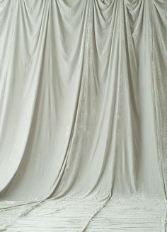 a person on a snowboard in front of a white curtained wall and floor