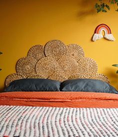 a bed with an orange blanket on top of it next to potted plants and a rainbow wall decal