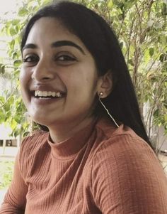 a woman smiling while sitting in front of a tree