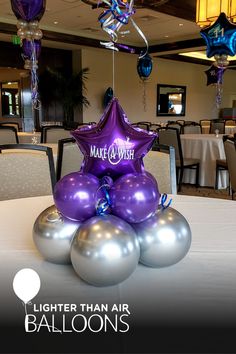 purple and silver balloons in the shape of stars on top of a table