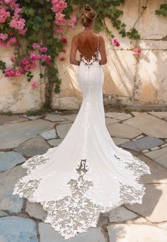 the back of a woman's wedding dress in front of pink flowers and vines