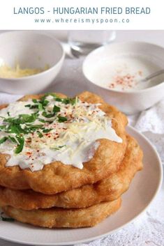 a stack of fried food sitting on top of a white plate next to two bowls