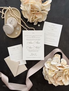 the wedding stationery is laid out with flowers and pearls