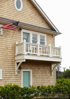 an american flag is flying in front of a house with a balcony and balconies