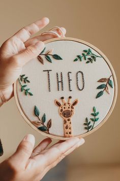 a person holding up a cross - stitch hoop with the word'tho'written on it