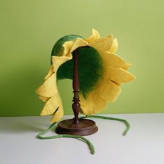 a yellow flower with green stems on a wooden stand