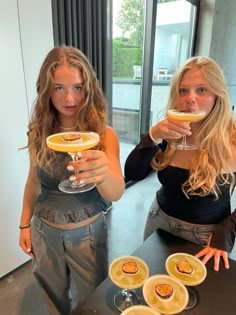 two beautiful young women holding wine glasses in front of them