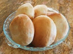 a glass bowl filled with rolls on top of a counter