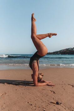 a woman doing a handstand on the beach