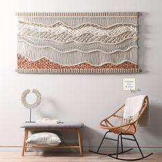 a chair and ottoman in front of a wall hanging