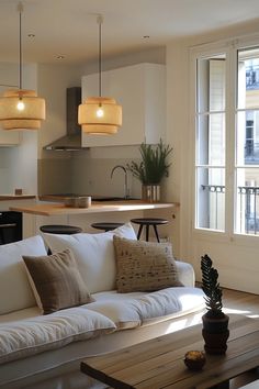 a living room filled with furniture next to a kitchen and an open floor plan in front of a window