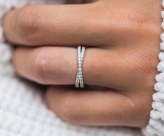 a woman's hand wearing a white diamond ring on top of her finger,