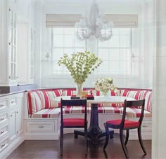 a kitchen with white cabinets and red striped cushions on the back of the couches