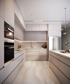 a modern kitchen with white cabinets and wood flooring, along with an oven on the wall