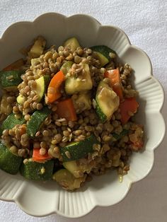 a white bowl filled with veggies and lentils on top of a table