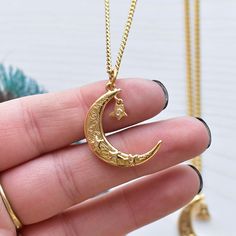 Looking for a celestial necklace with lots of magic and luck? This necklace is it! This necklace is made from a crescent moon charm. The moon charm has three stars with clear cz centers on the front. On the front of the moon the words; magic, luck and love can be seen along with a peace sign and an evil eye. A star drop hangs from the moon. The star like the others has a clear cz crystal in the center. The pendant is gold plated and has a shiny surface. The necklace is finished off with a stainl Celestial Crescent Jewelry With Star Charm, Good Luck Moon Charm Pendant Jewelry, Spiritual Crescent Moon Phase Necklaces, Magical Moon Phase Jewelry, Spiritual Crescent Moon Phase Necklace, Magical Crescent Moon Charm Jewelry, Spiritual Round Moon Charm Necklace, Spiritual Gold Charm Necklace With Moon Charm, Magical Sun And Moon Design Necklace Gift