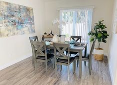 a dining room table with chairs and a painting on the wall in front of it