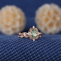 a ring with an oval green stone surrounded by smaller round stones on a blue cloth