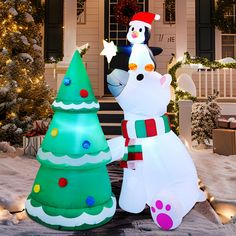 two large inflatable christmas trees and a snowman on the front steps of a house