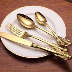 gold colored forks and spoons on a white plate