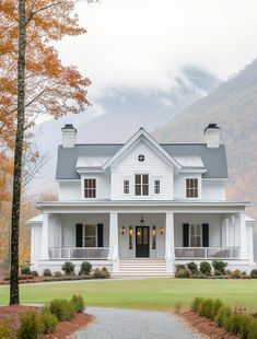 a large white house with black shutters on the front and side windows, surrounded by fall foliage